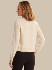 Woman wearing a beige sweater against a plain background
