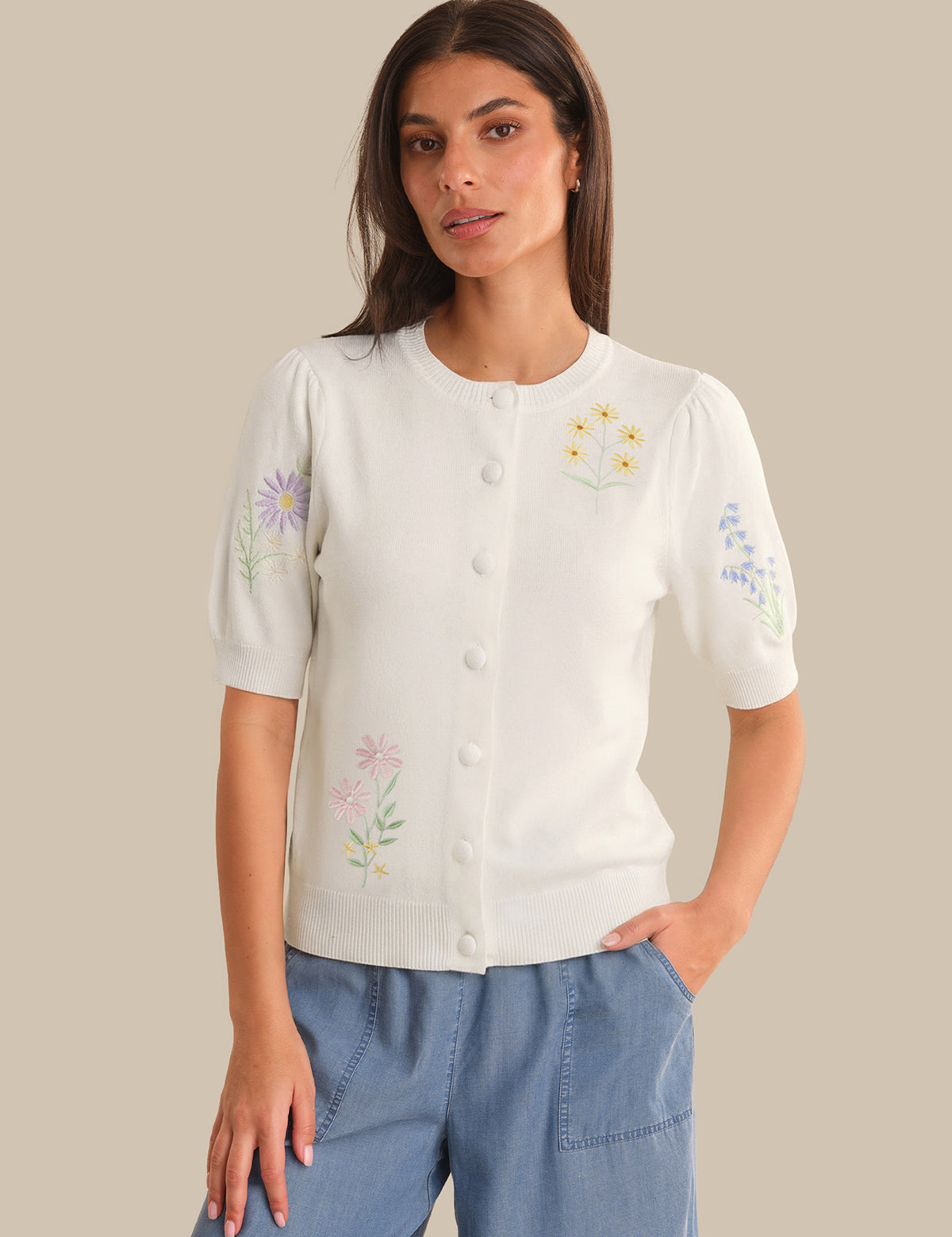 Woman wearing a white blouse with floral embroidery on a beige background