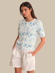 Woman wearing a floral cardigan and white shorts against a beige background