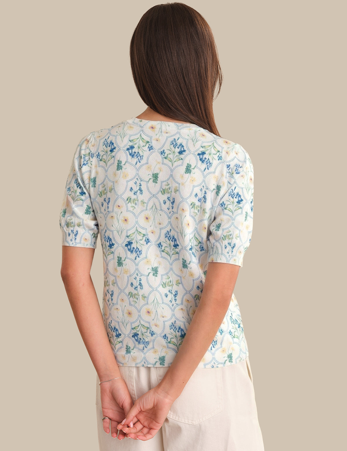 Woman wearing a floral-patterned cardigan against a beige background