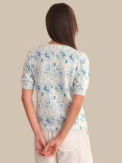 Woman wearing a floral-patterned cardigan against a beige background