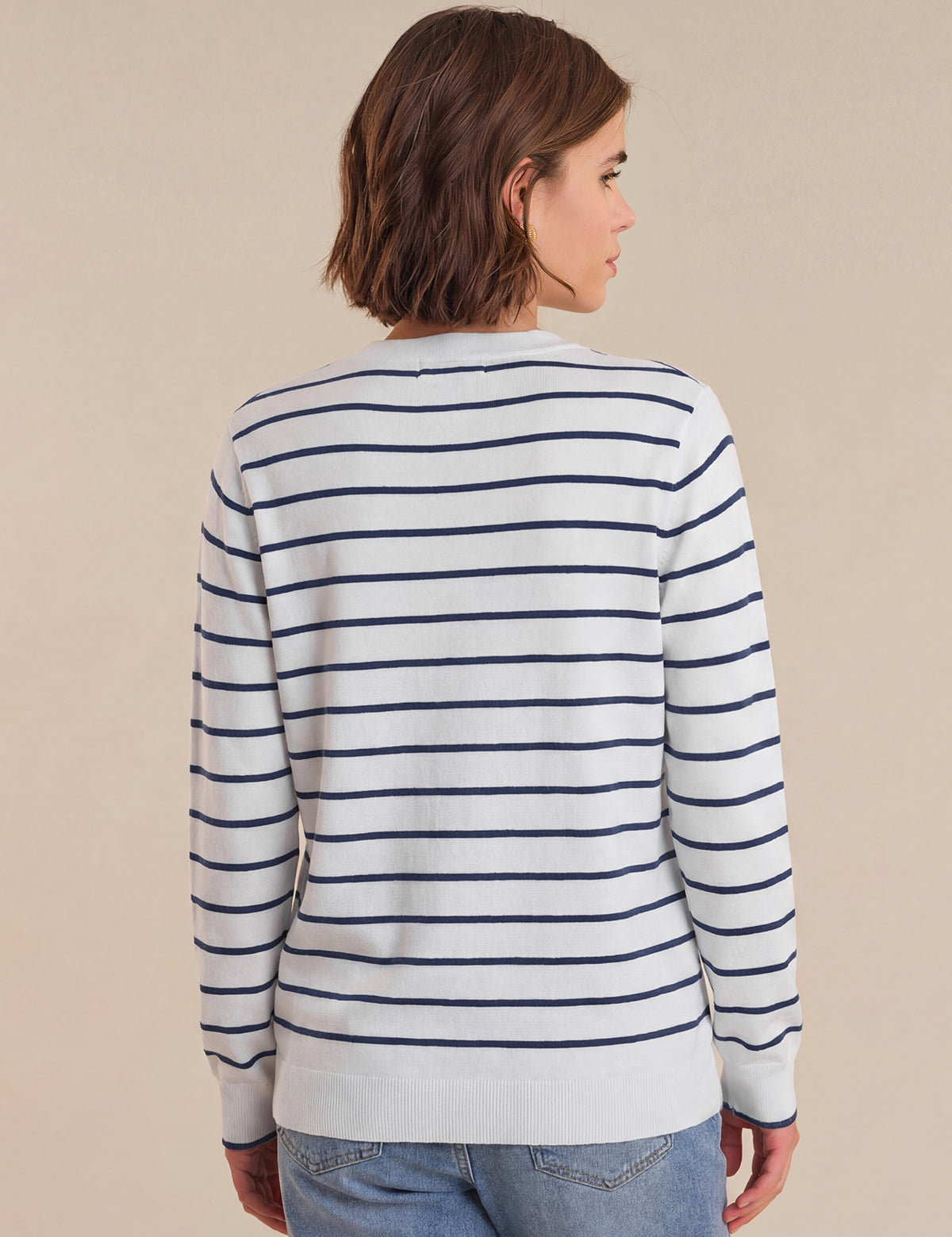 Person wearing a striped long-sleeve shirt against a beige background