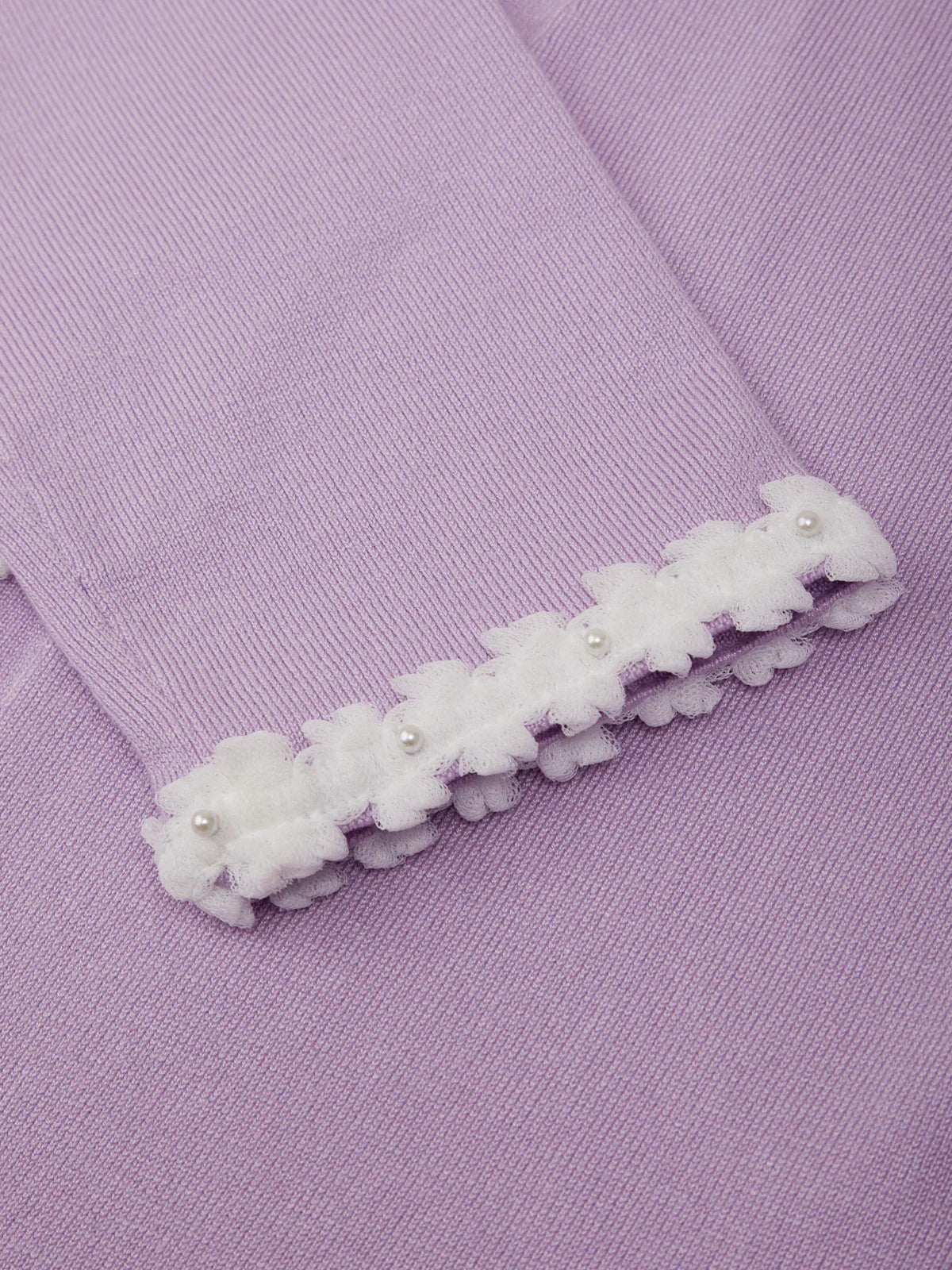 White floral hair clip on a purple fabric background