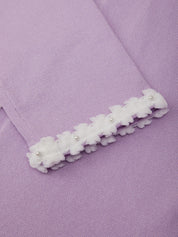 White floral hair clip on a purple fabric background