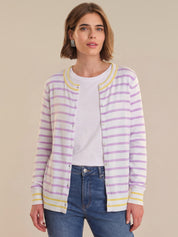 Woman wearing a striped cardigan over a white shirt with blue jeans on a beige background