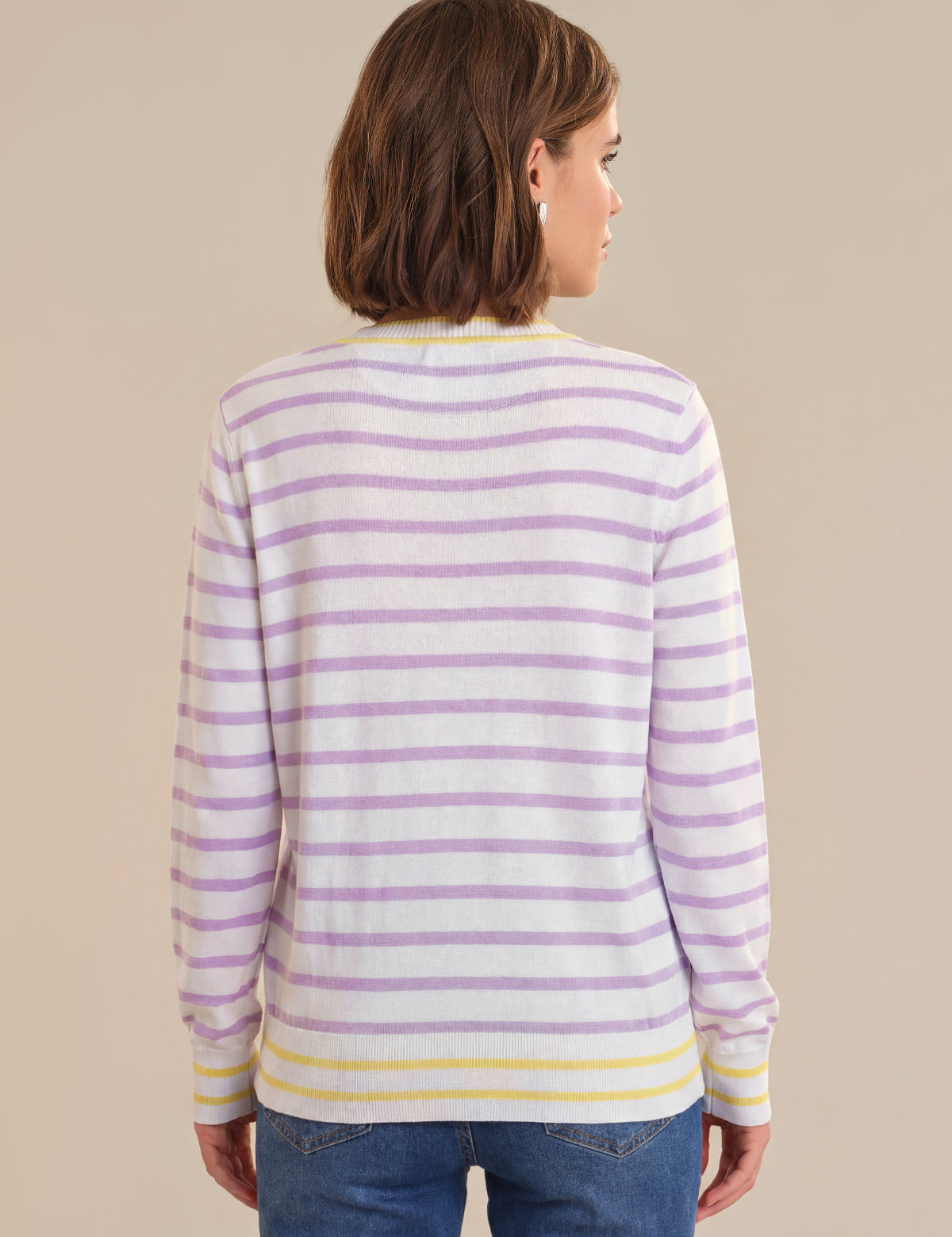 Woman wearing a striped sweater with purple and yellow stripes on a beige background