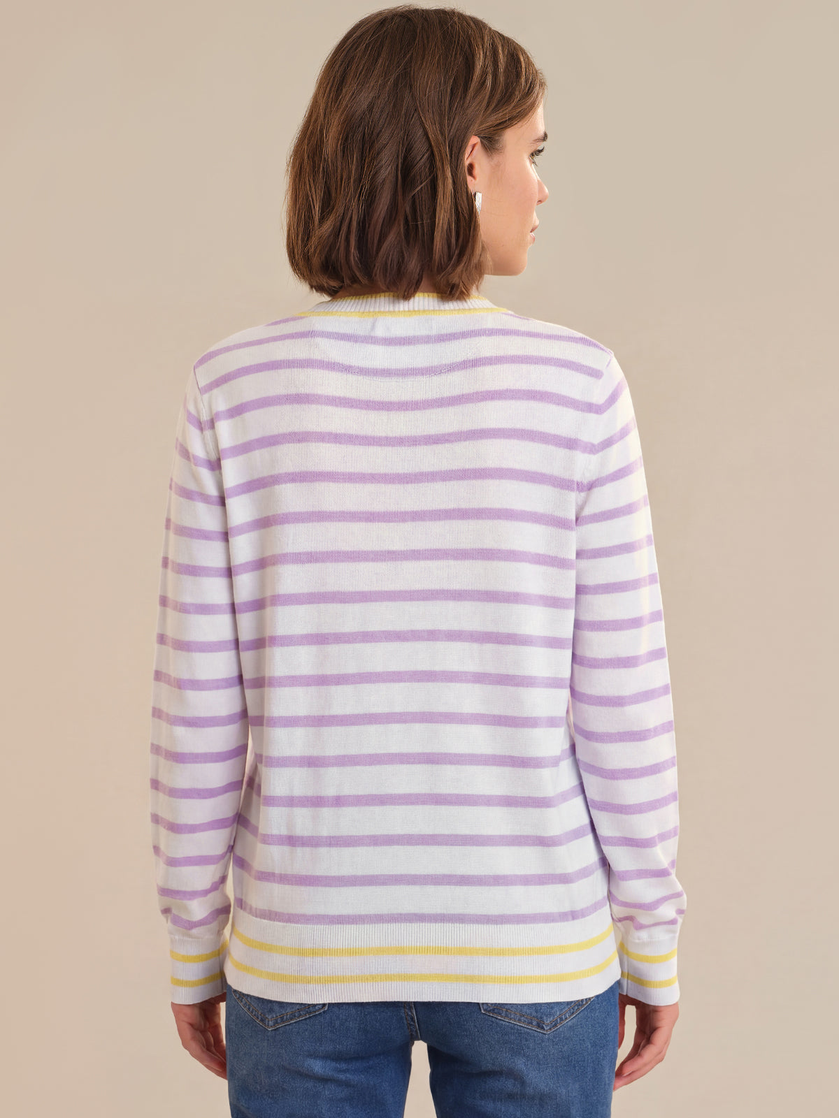 Woman wearing a striped sweater with purple and yellow stripes on a beige background