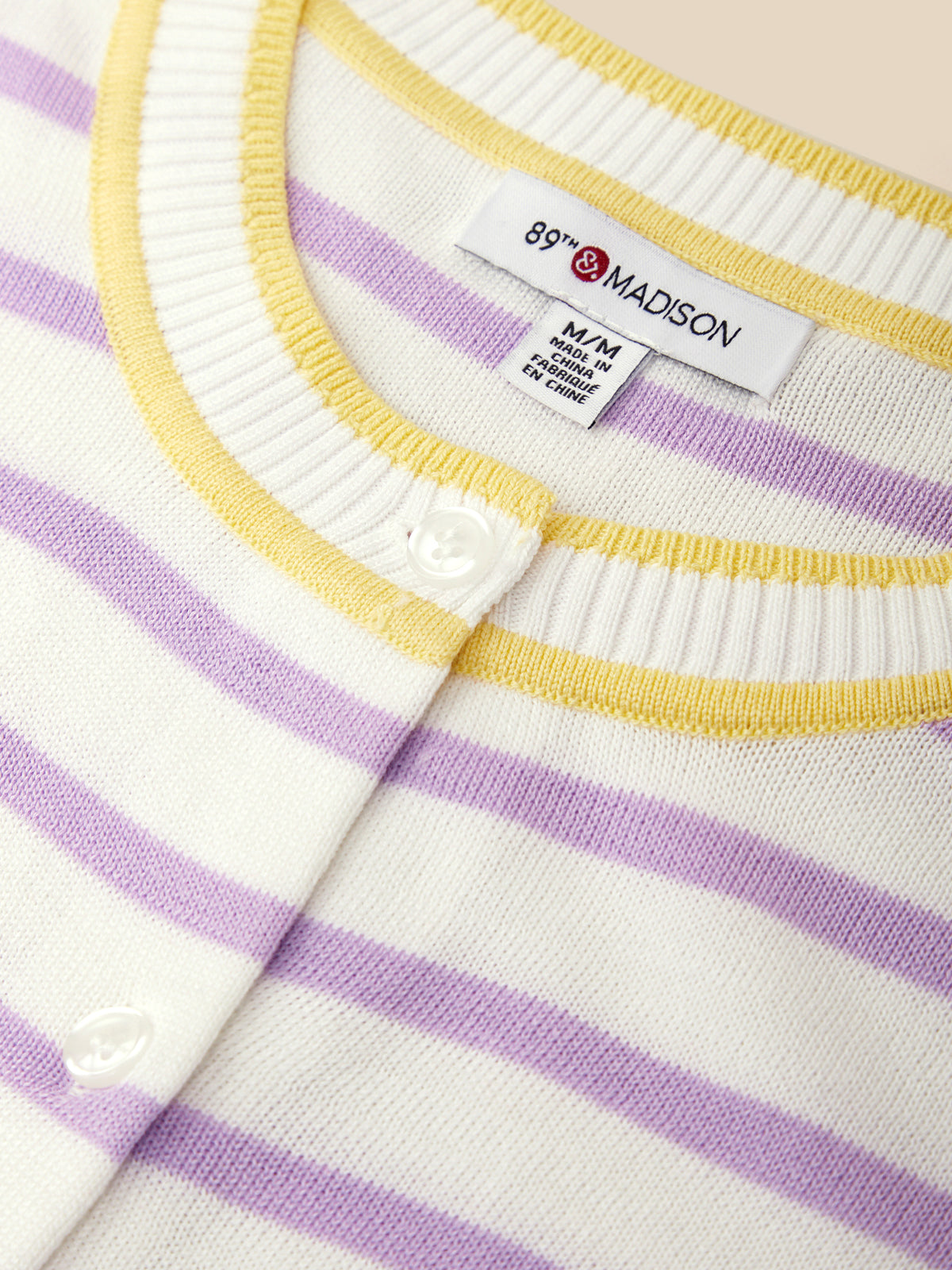 Close-up of a baby cardigan with purple and yellow stripes and a visible brand label.
