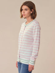 Woman wearing a pastel striped cardigan against a beige background