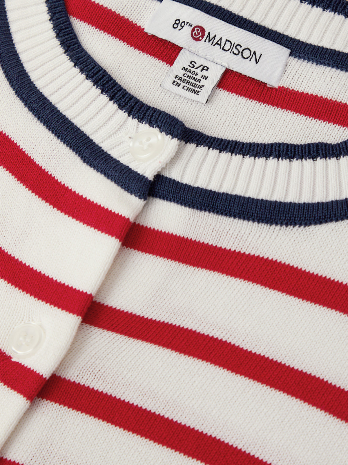 Close-up of a striped sweater with a brand label on a white background