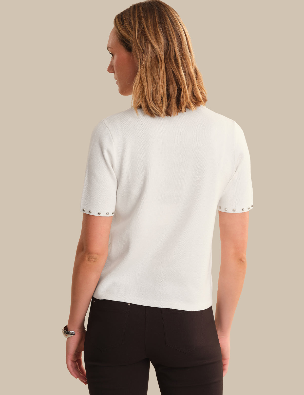 Woman wearing a white short-sleeve shirt with black trim on a beige background