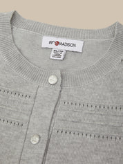 Close-up of a light gray knit cardigan sweater showing the inner neck label which reads '89th & MADISON' and 'XS/XXL', along with two white buttons on the front.