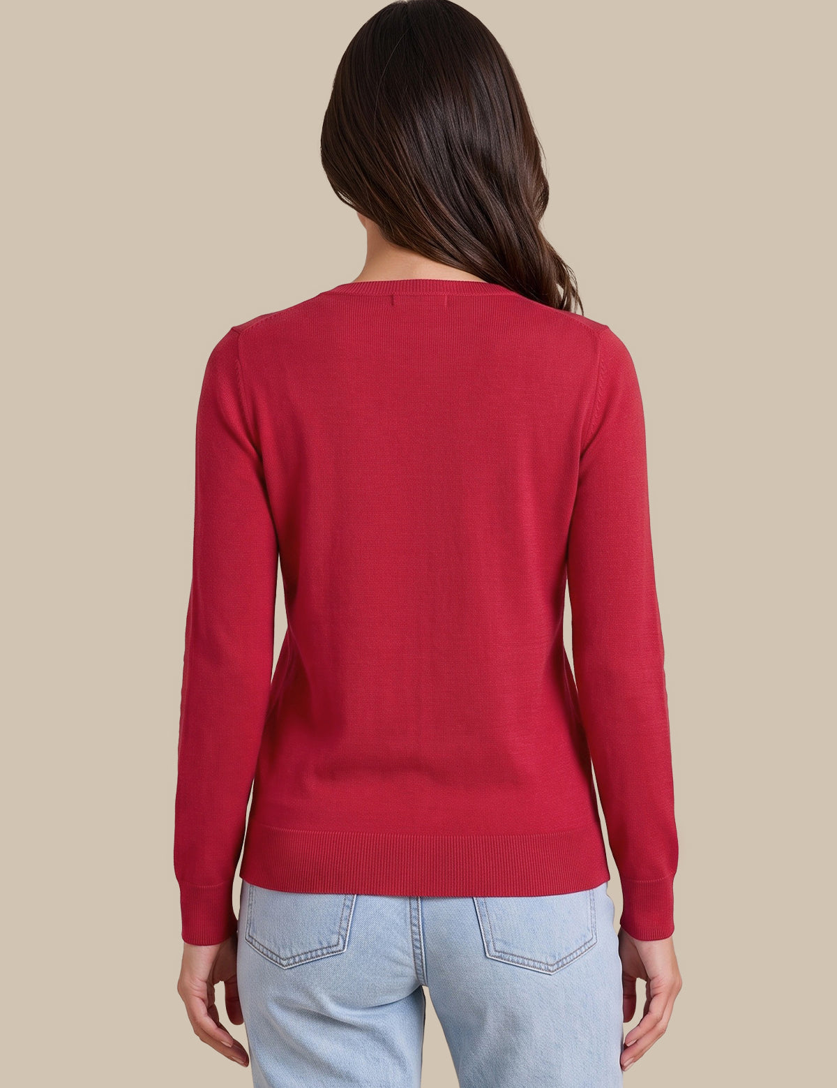 A woman viewed from the back wearing a solid red long-sleeve knit sweater and light blue jeans, set against a solid beige studio background.