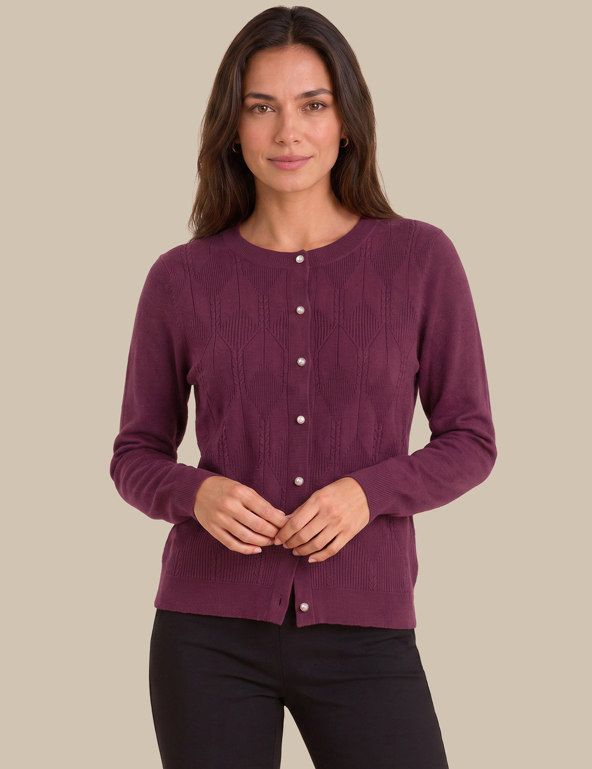 A woman modeling a long-sleeve crewneck cardigan sweater in a deep plum purple color, featuring a button-down front and textured knit pattern, set against a solid beige background.