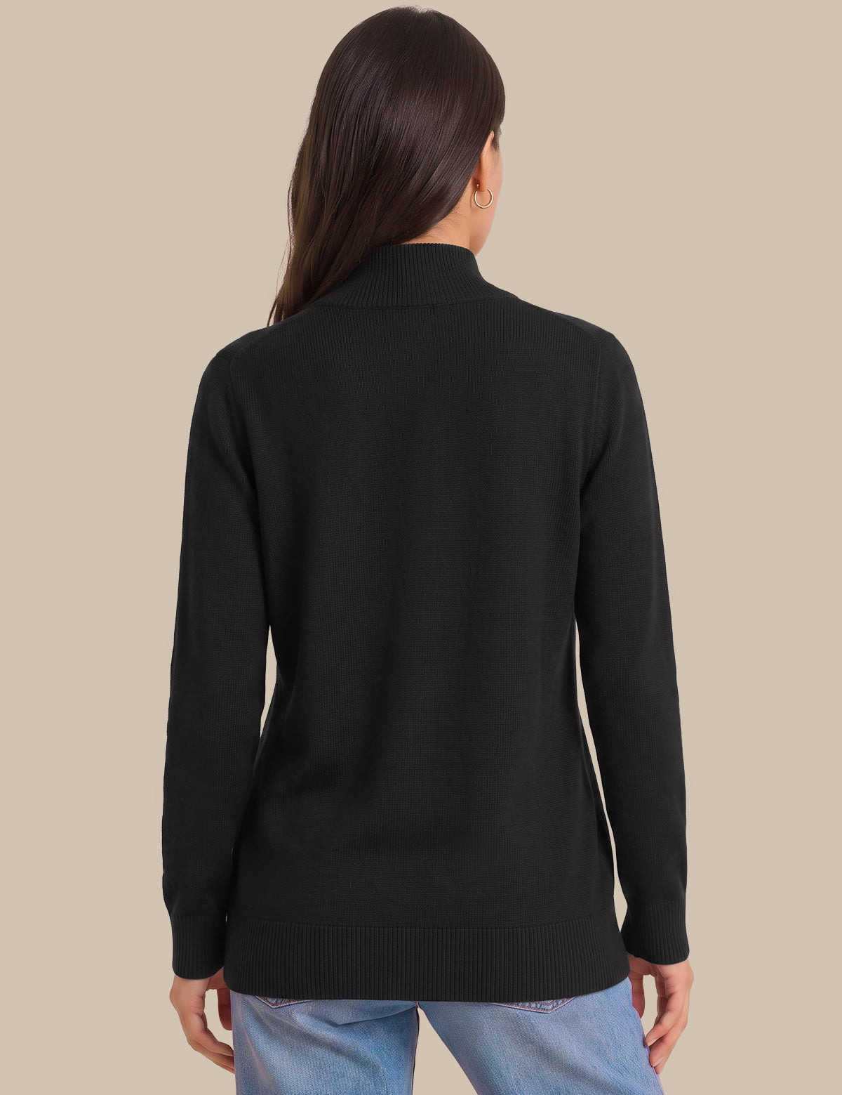 A woman viewed from the back wearing a black mock-neck knit sweater and light blue jeans, set against a solid beige background.
