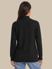 A woman viewed from the back wearing a black mock-neck knit sweater and light blue jeans, set against a solid beige background.