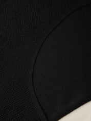 Close-up detail of a black knit garment showing the textured fabric and curved seam.