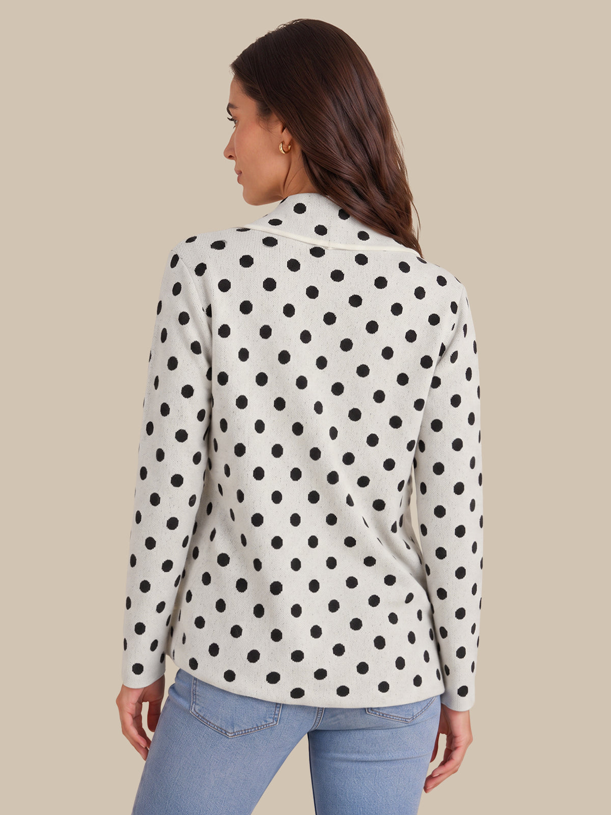 A woman shown from the back wearing a white long-sleeve blazer with a black polka dot pattern, paired with light blue jeans, against a solid beige background.