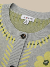 Close-up of a gray knit cardigan sweater with yellow and green geometric and floral patterns, featuring a white tag with the brand name '89 MADISO' inside the collar.