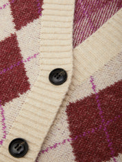 Close-up of a knit cardigan with a cream ribbed collar and placket, featuring a diamond argyle pattern in burgundy and magenta with black buttons.