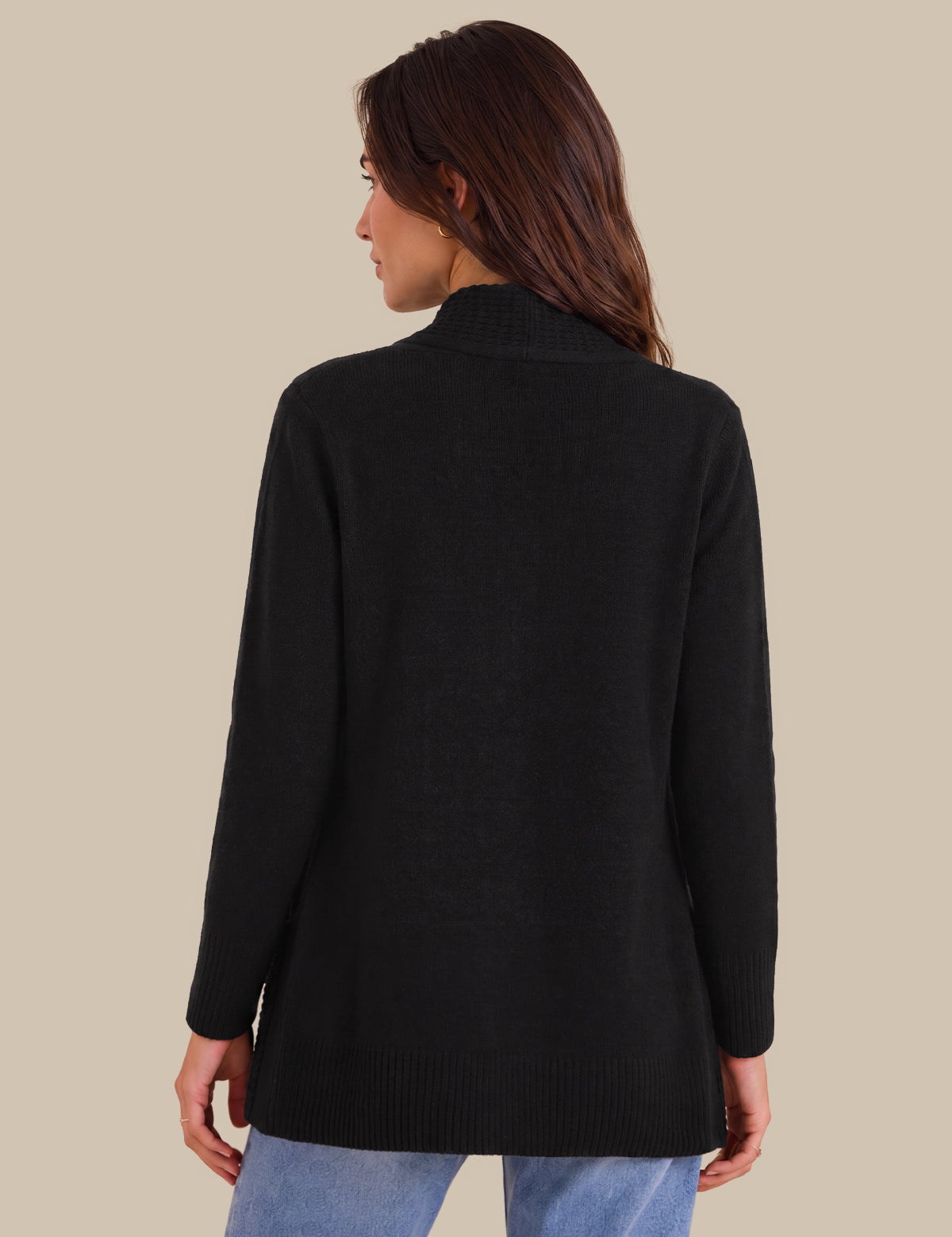A woman shown from the back wearing a black long-sleeve knit sweater and light blue jeans against a solid beige background.