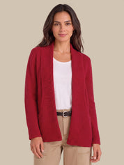 A woman modeling a red waffle-knit open-front cardigan over a white top and beige pants, set against a solid beige background.