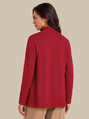 A woman shown from the back wearing a red knit sweater with a mock neck and ribbed cuffs, paired with beige pants, against a solid beige background.
