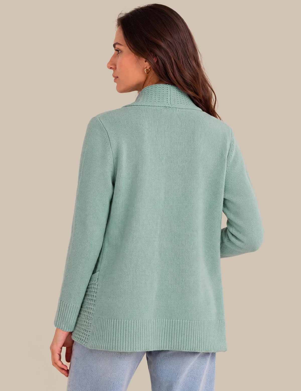 A woman shown from the back wearing a mint green knit cardigan with a mock neck and ribbed cuffs and hem, paired with light blue jeans, against a solid beige background.