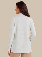 A woman shown from the back wearing a lvory knit sweater with a mock neck and long sleeves, set against a solid beige background.