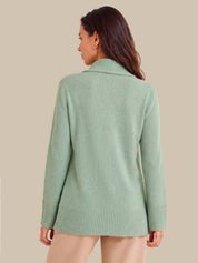 A woman shown from the back wearing a light sage green knit sweater with a wide collar and ribbed cuffs and hem, against a solid beige background.