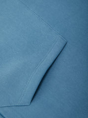 Close-up of a blue fabric surface with a folded corner showing fine woven texture and neat stitching.