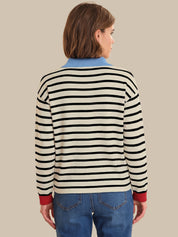 Person wearing a black and white striped sweater with red cuffs and hem on a beige background