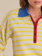 Close-up of a person wearing a yellow and white striped shirt with a blue collar and red buttons.