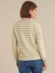 Person wearing a striped sweater and blue jeans against a beige background
