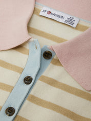 Close-up of a baby outfit with striped pattern and pink accents, featuring a label.