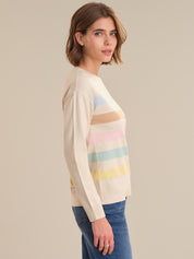 Woman wearing a cream sweater with colorful stripes on a beige background