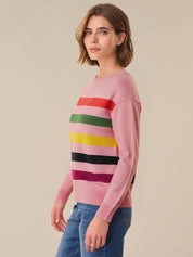 Woman wearing a pink sweater with colorful horizontal stripes on a beige background