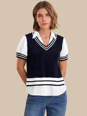 Woman wearing a navy and white striped sweater over a white shirt with blue jeans on a beige background
