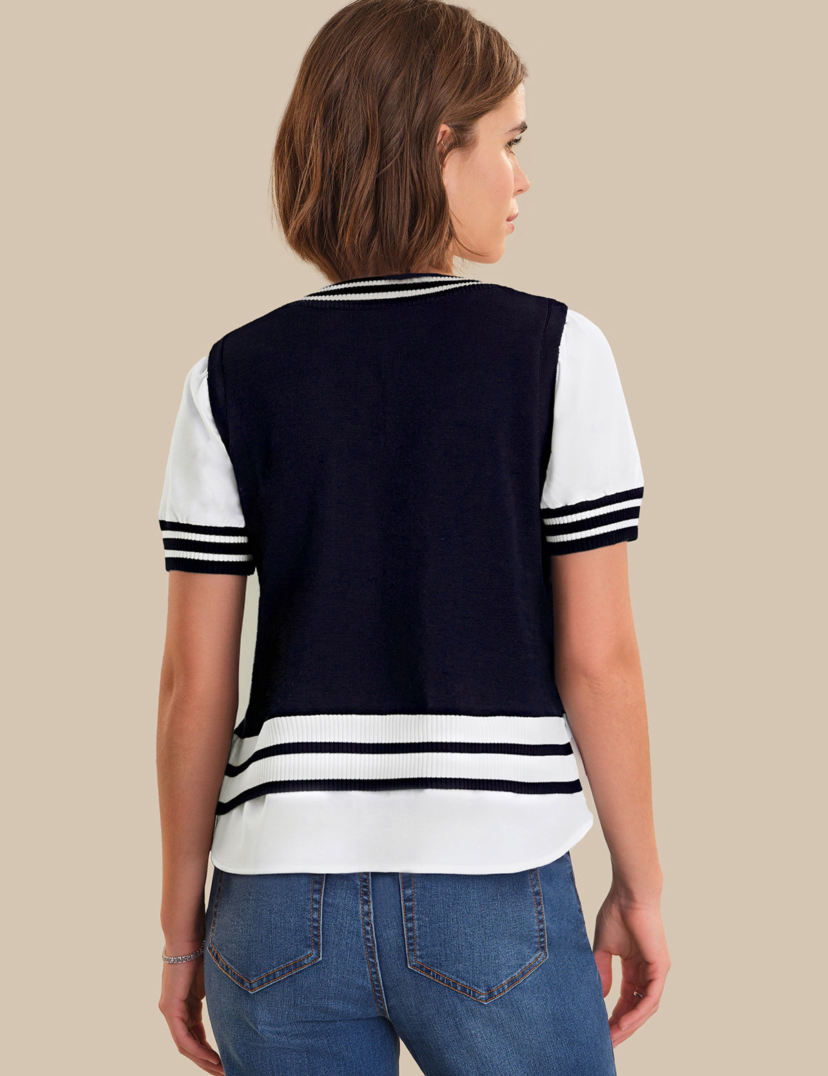 Woman wearing a navy and white striped shirt with blue jeans on a beige background