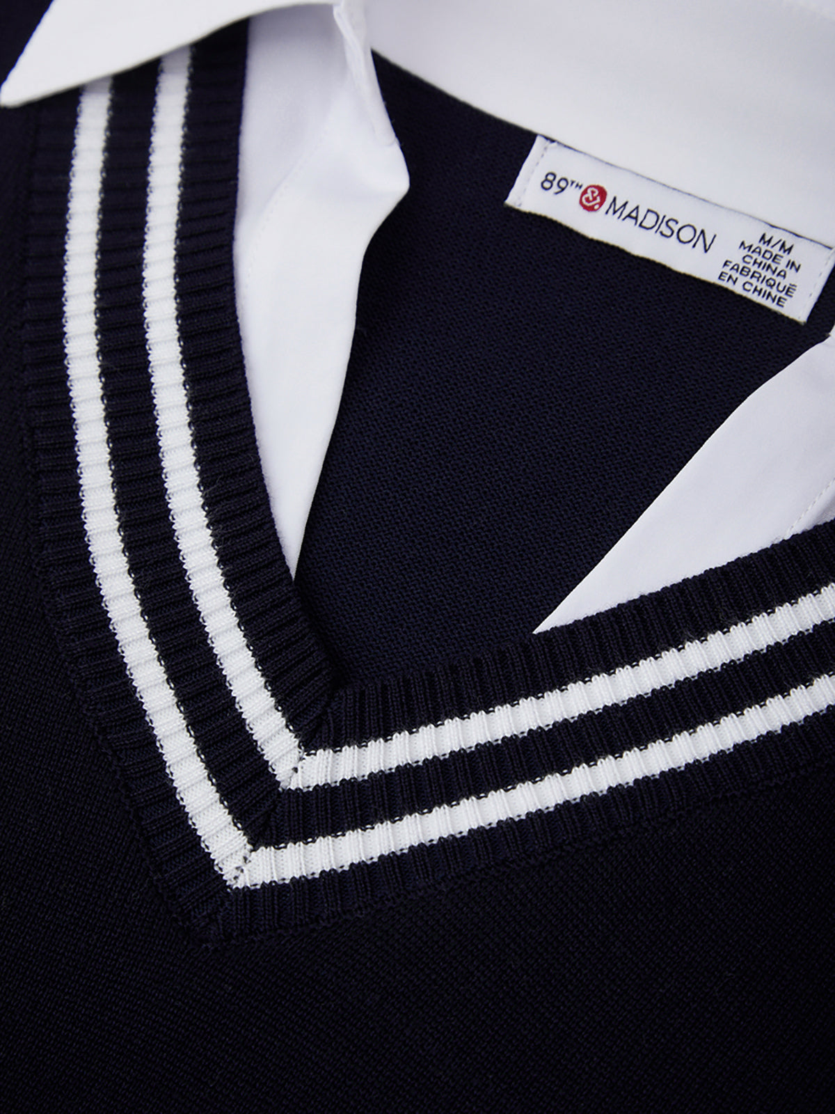 Close-up of a black sweater with white trim and a visible brand label.