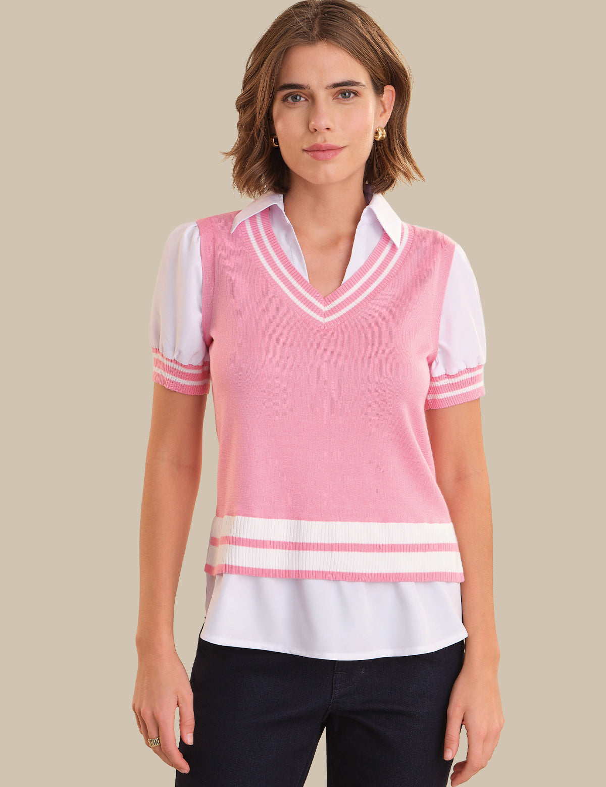 Woman wearing a pink and white striped sweater vest over a white shirt on a beige background