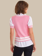 Person wearing a pink and white sweater vest over a white shirt on a beige background