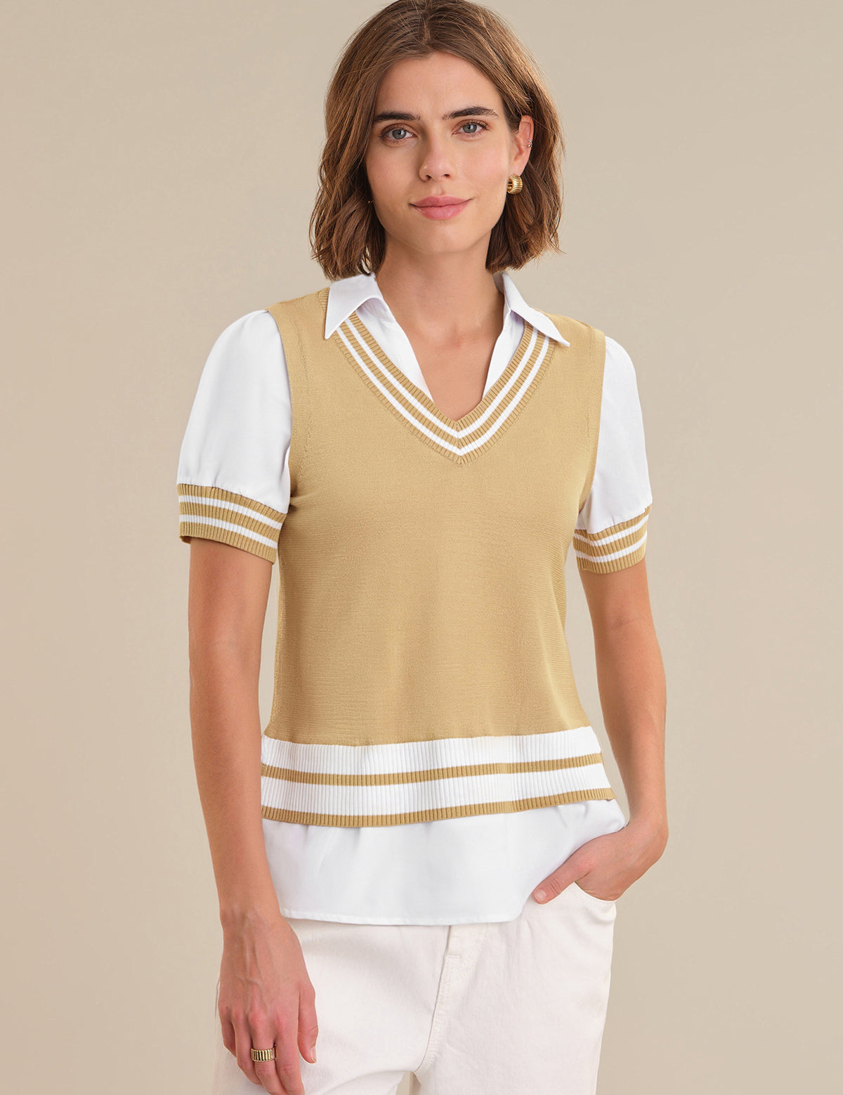 Woman wearing a beige and white striped sweater vest over a white shirt on a beige background