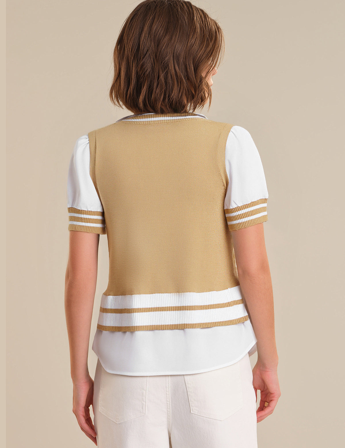 Woman wearing a beige and white striped sweater over a white shirt on a beige background