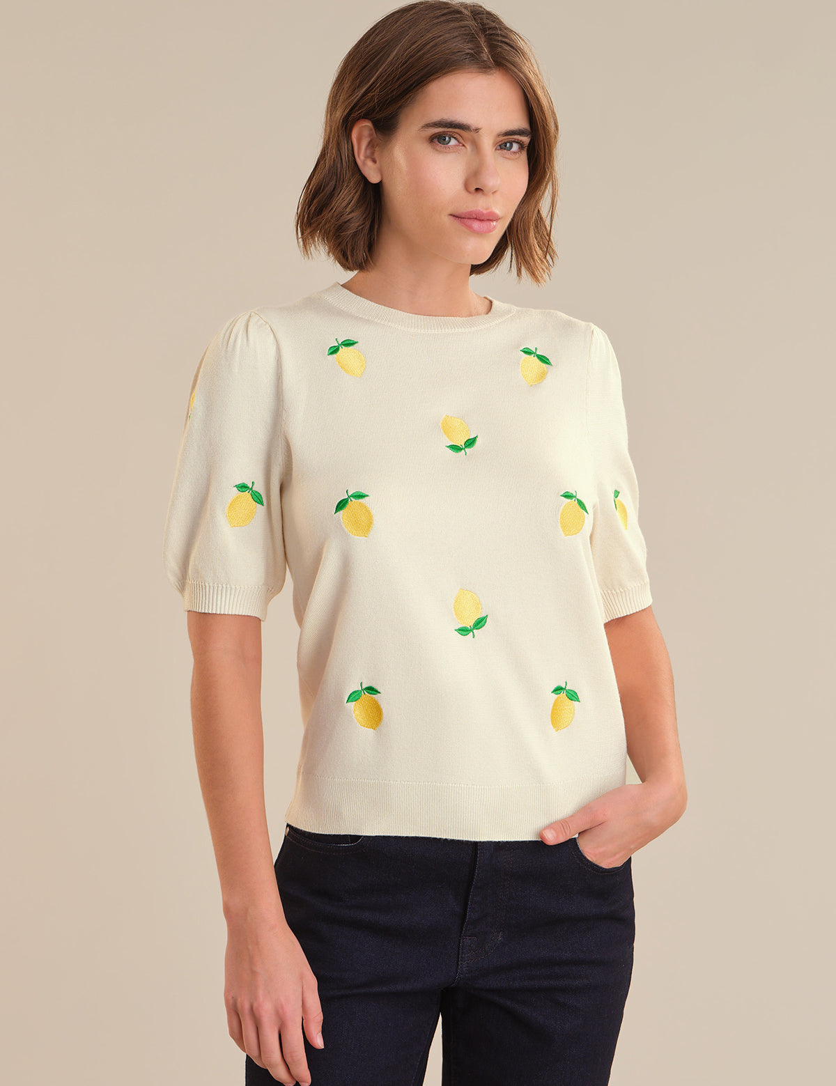 Woman wearing a cream-colored top with lemon designs on a beige background