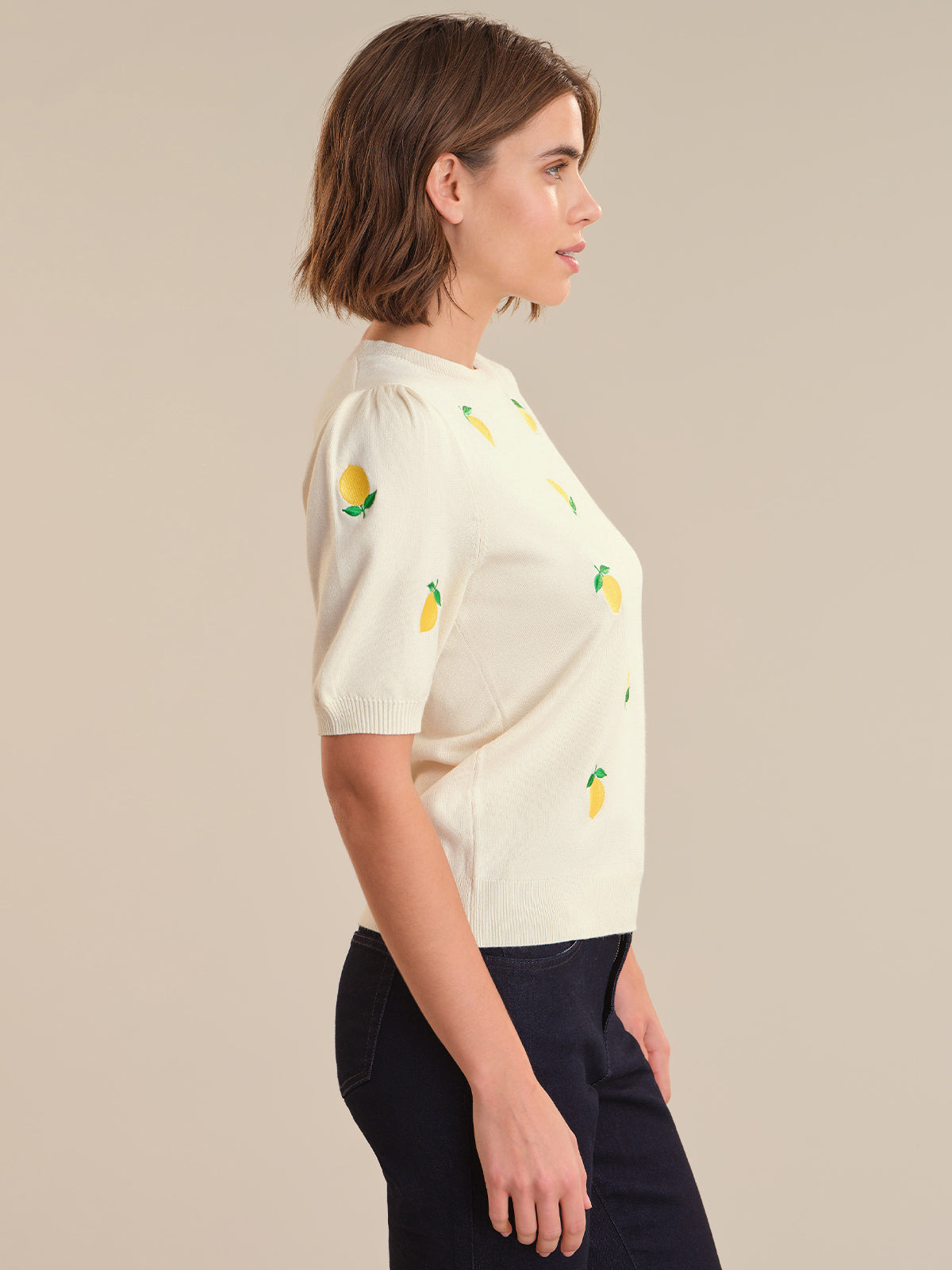 Woman wearing a cream-colored blouse with pineapple patterns on a beige background