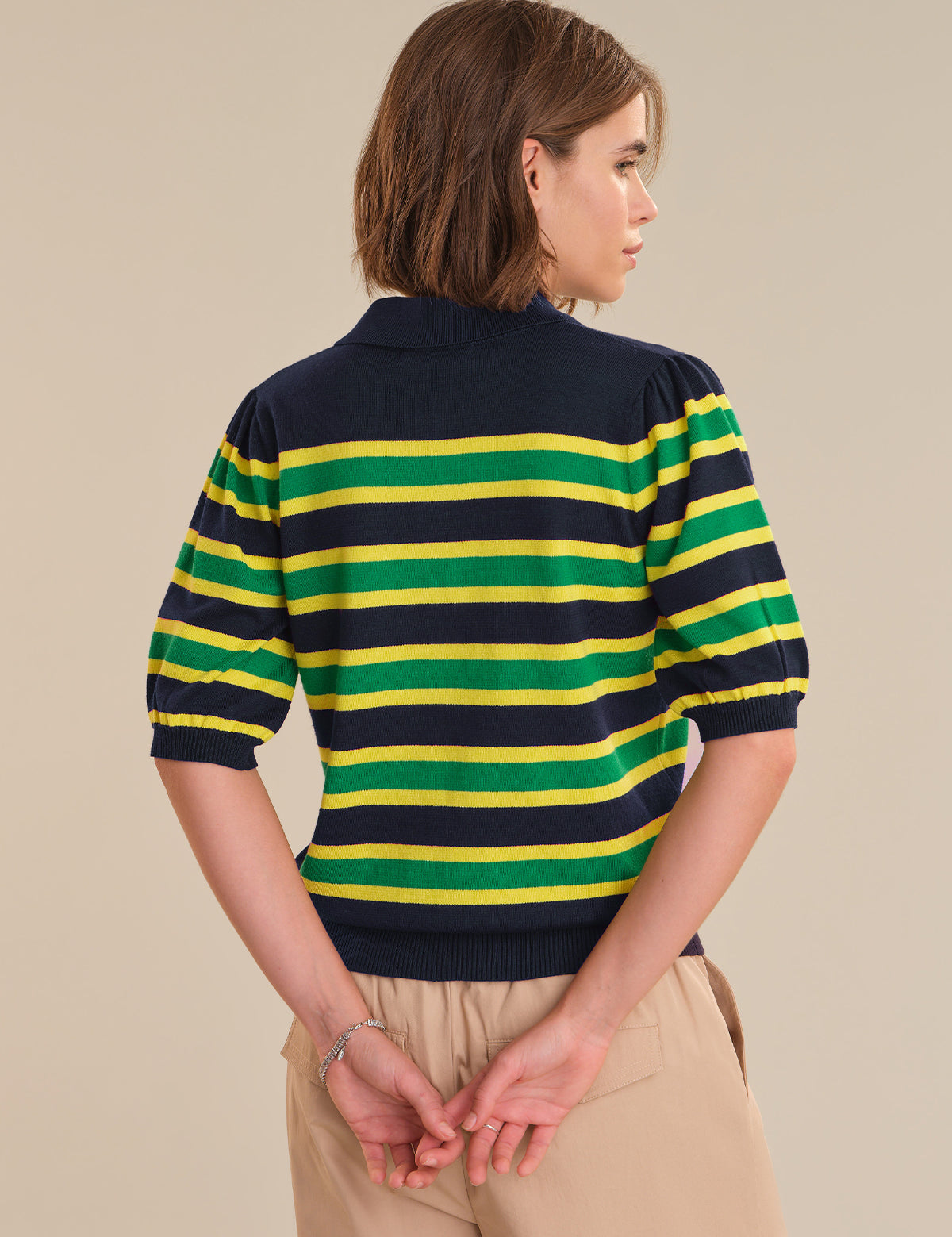 Person wearing a green and yellow striped sweater on a beige background