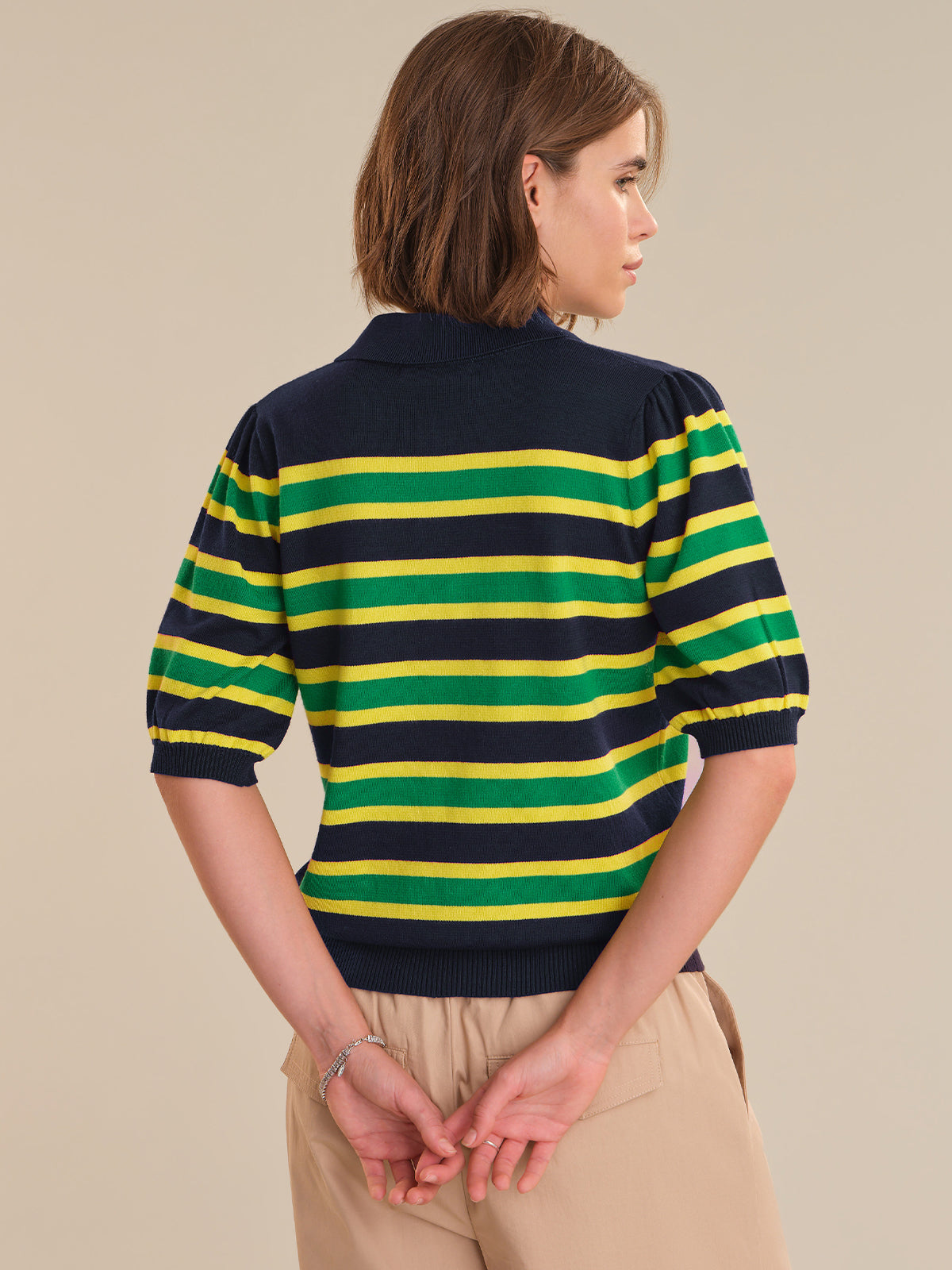Person wearing a green and yellow striped sweater on a beige background