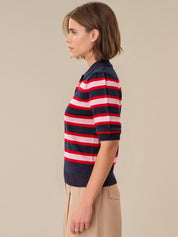 Person wearing a navy, red, and white striped shirt against a beige background