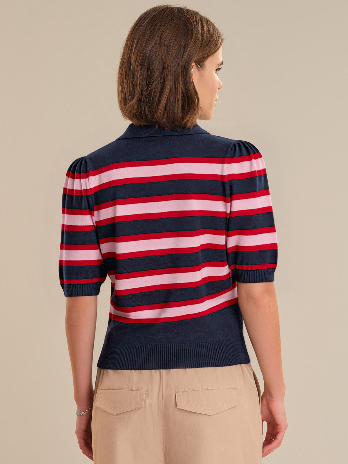 Woman wearing a red, white, and blue striped sweater on a beige background